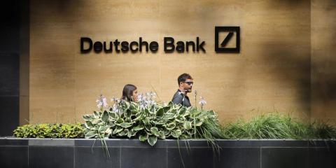 People walk past a Deutsche Bank office in London People walk past a Deutsche Bank office in London