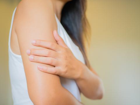 Una mujer se toca el brazo con la mano Una mujer se toca el brazo con la mano