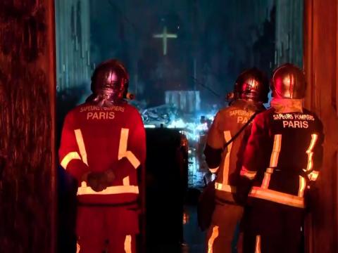 In this image taken from France Televisions video, firefighters stand at an entrance and look at the fire damage inside the Notre Dame cathedral in Paris, Monday April 15, 2019.