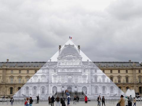 Los turistas caminan alrededor del proyecto JR en el Louvre en París, Francia, en 2016.