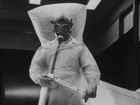 Trabajador vestido con trajes de plástico de polietileno reparando la parte radiactiva de la central atómica en 1954.