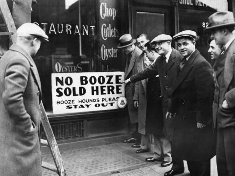 People by a Prohibition sign reading, "No booze sold here."