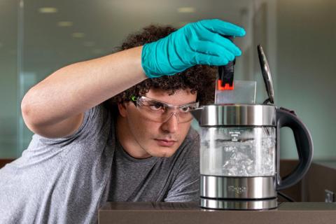 A researcher putting the glass in boiling water to test its resilience.