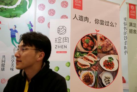 Un hombre junto a un póster del stand de la compañía de Zhenmeat en la feria VeggieWorld de Pekín.