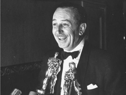 Walt Disney holding four Oscars.