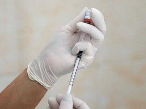 A nurse fills a syringe with a vaccine.