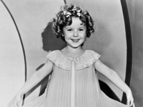Shirley Temple as a child star wearing an accordion pleated dress.