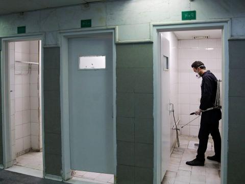 Un miembro del equipo médico rocía desinfectante para higienizar los baños.
