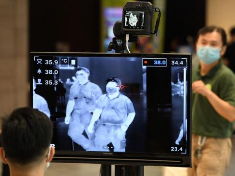 A man wearing a protective facemask walks past a temperature screening check at Changi International airport in Singapore on February 27, 2020.