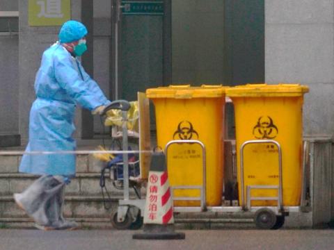 Un miembro del personal mueve contenedores de biorresiduos por delante de la entrada del Centro de Tratamiento Médico de Wuhan, China, donde se está tratando a personas infectadas con COVID-19, el pasado 22 de enero.