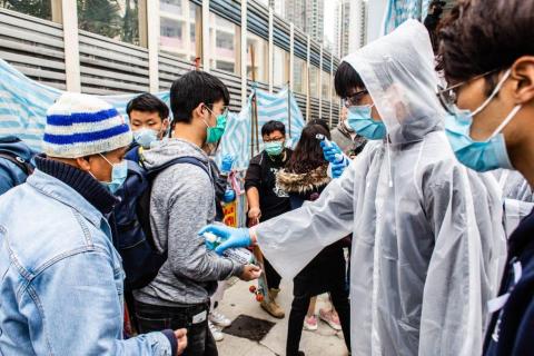 Un voluntario ofrece desinfectante de manos a los pasajeros.