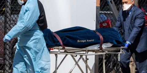 A funeral director and a medical-center employee transport a body in New York City on April 1.