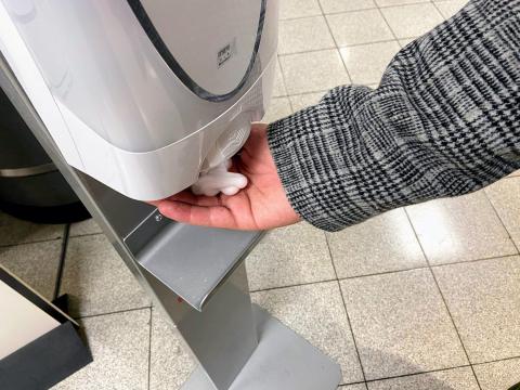 A person reaching for hand sanitizer.