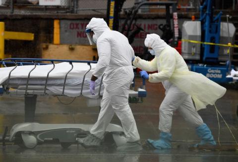 Personal médico traslada a un paciente fallecido a un camión frigorífico que sirve como morgue improvisada en el Centro Hospitalario de Brooklyn el 9 de abril de 2020, en la ciudad de Nueva York.