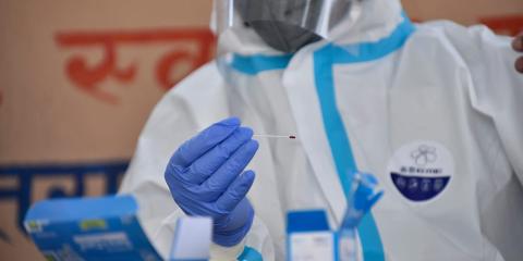 A health worker in protective gear takes a blood sample from a woman to test for the coronavirus on Wednesday, April 15, 2020.