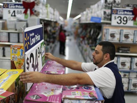 A worker adjusting a sign at a Walmart.
