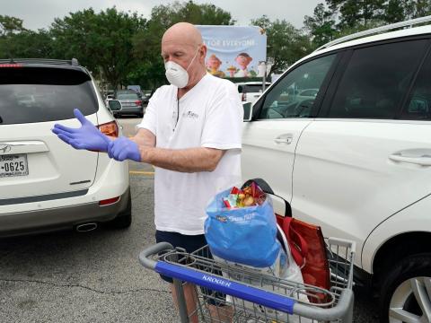 Gary Towler puts on gloves to protect against coronavirus, before entering a grocery store Wednesday, April 22, 2020, in Spring, Texas.