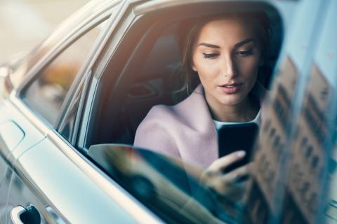 Mujer en el coche mirando el iPhone