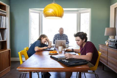 Father, daughter and son are at the table with a computer each.