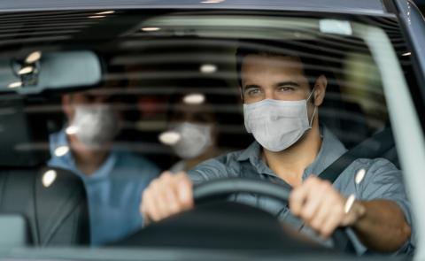 Una persona conduce un coche con un pasajero en la parte de atrás.