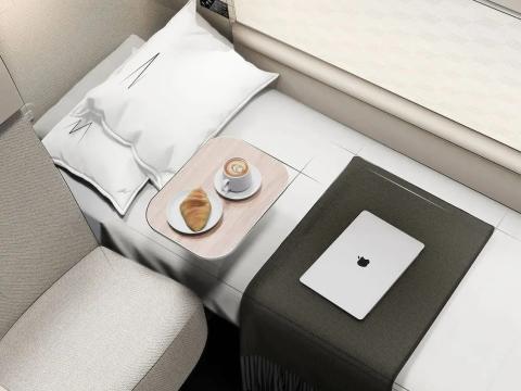 The Qantas A350 first suite has a bed, seating area, and coffee and pastries on a tray.