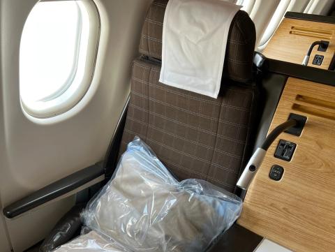 A SwissAir business-class seat with blanket and pillow stacked on top