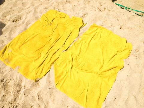 Two yellow beach towels laid out on the sand