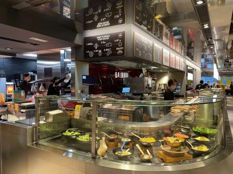A salad bar in a warehouse-style McDonald's with employees working behind counter