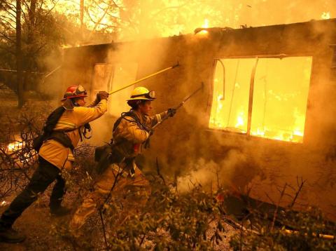 Firefighters try to keep flames from a burning home from spreading to a neighboring apartment complex as they battle the Camp Fire on November 9, 2018 in Paradise, California. Firefighters try to keep flames from a burning home from spreading to a neighboring apartment complex as they battle the Camp Fire on November 9, 2018 in Paradise, California.