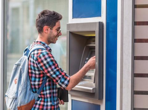 Joven sacando dinero de un cajero autómatico Joven sacando dinero de un cajero autómatico