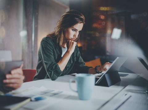 Una empresaria mira su tablet en su oficina Una trabajadora preocupada consulta los datos de su empresa