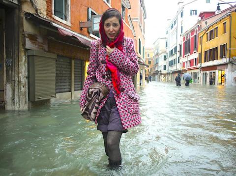 Una mujer intenta caminar por una calle inundada en Venecia. Una mujer intenta caminar por una calle inundada en Venecia.