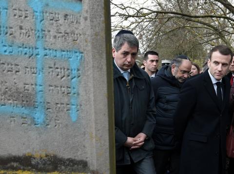 Emmanuel Macron pasa junto a una lápida hebrea con una hesvástica pintada Emmanuel Macron pasa junto a una lápida hebrea con una hesvástica pintada