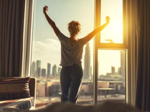 Una mujer mira por la ventana tras despertarse Una mujer mira por la ventana tras despertarse