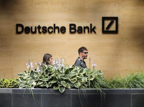 People walk past a Deutsche Bank office in London People walk past a Deutsche Bank office in London