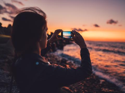 Una mujer haciendo una foto al horizonte con un teléfono Una mujer haciendo una foto al horizonte con un teléfono