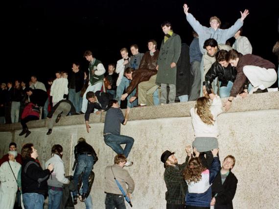 East Germans celebrate as they climbed the Berlin Wall at the Brandenburg Gate November 10, 1989.