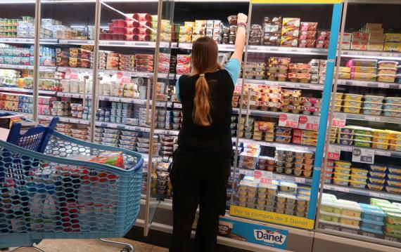 Una mujer coge yogures en un supermercado. 