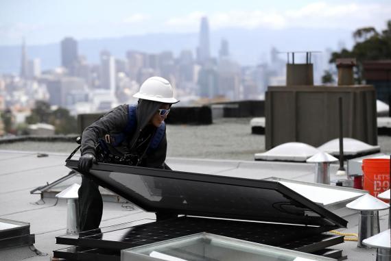 Una mujer mueve un panel solar durante su instalación en un tejado en San Francisco, California.