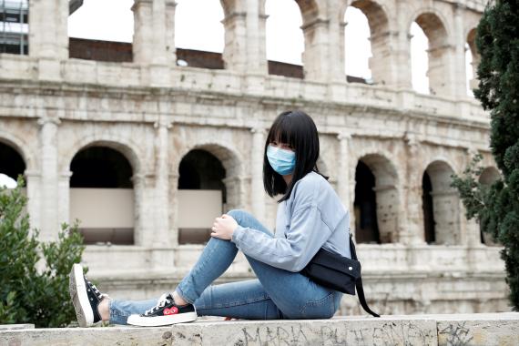 Una turista con una mascarilla posa ante el Coliseo de Roma, en Italia.
