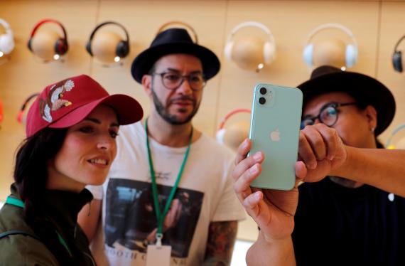 Usuarios de Apple en una de sus tiendas observando en funcionamiento de un iPhone.